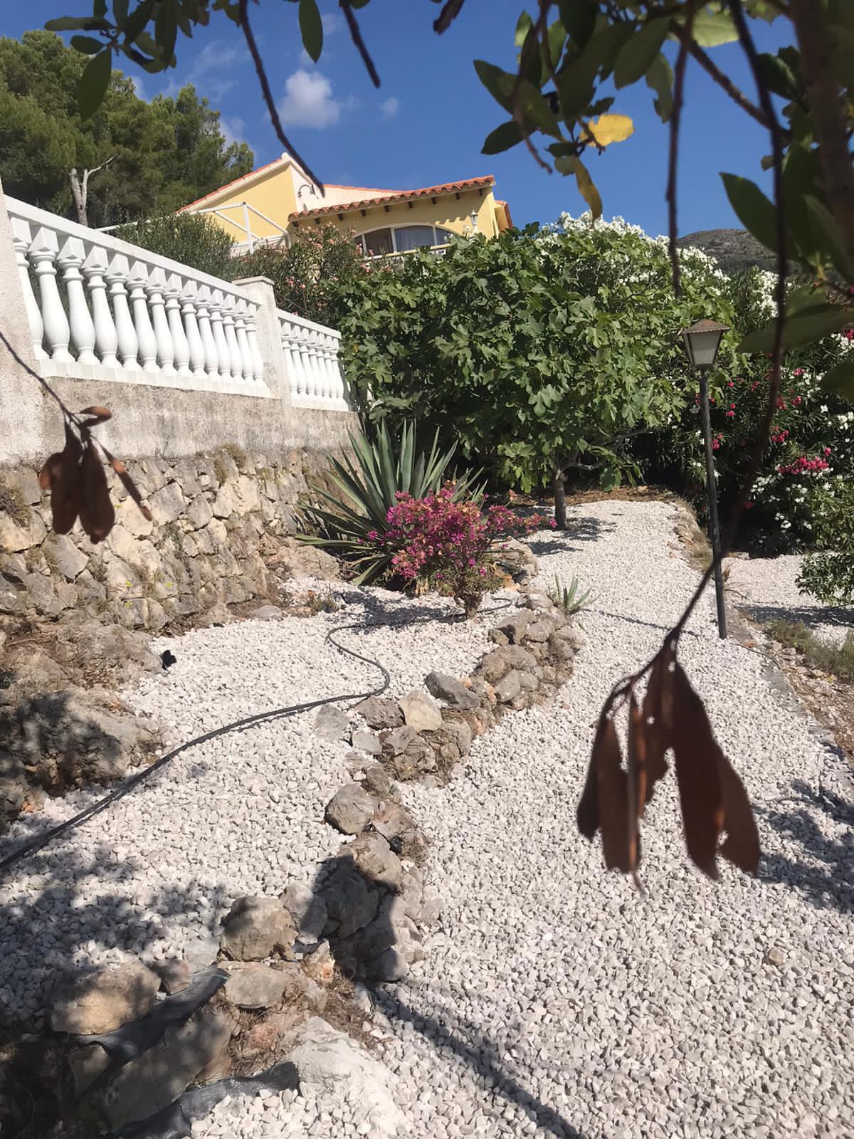 Mediterraner Garten mit Kieswegen, Steinmauern und Pflanzen