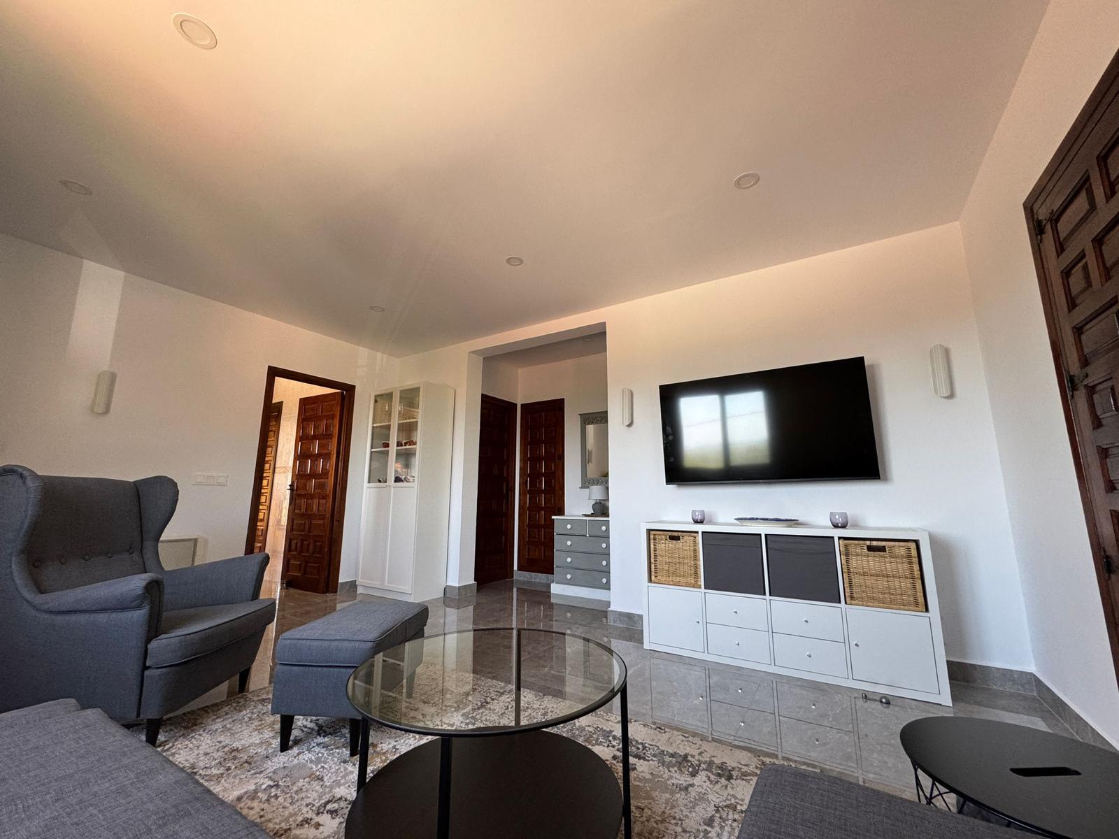 Wohnzimmer mit Sessel, TV und hellem Boden