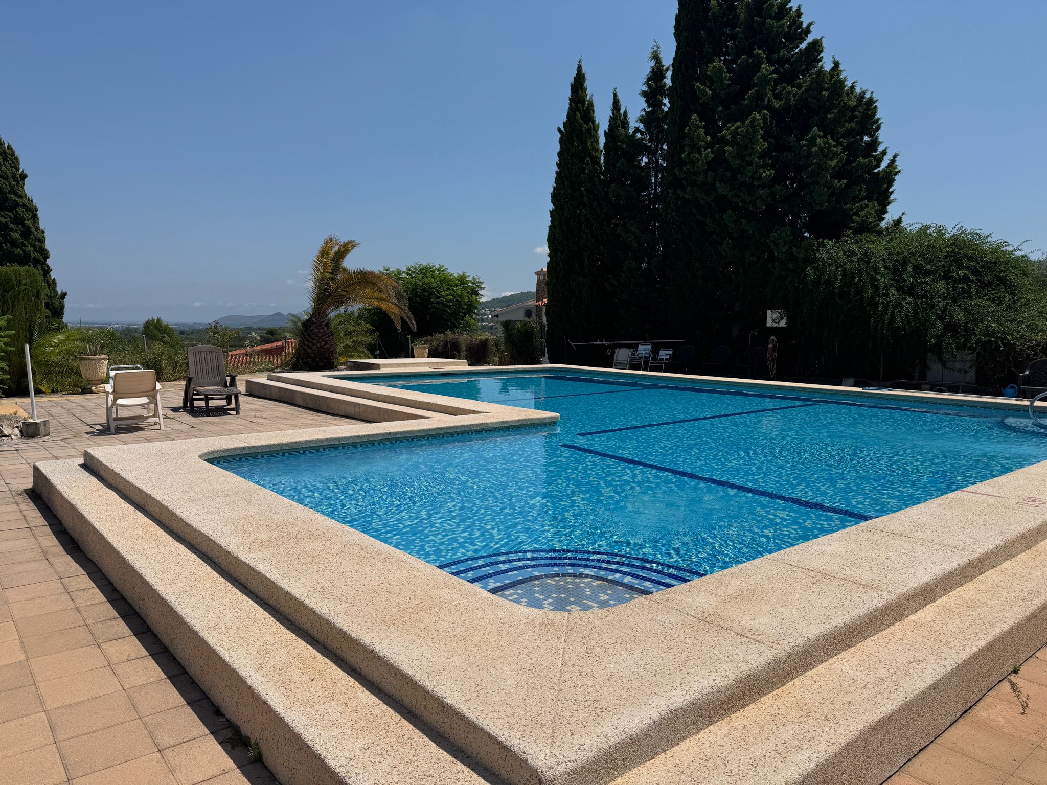 Großer Gemeinschaftspool mit Liegeflächen und Bergen im Hintergrund